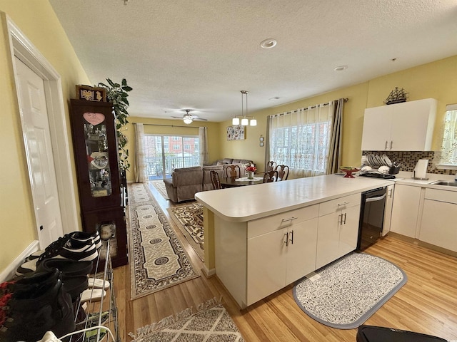 kitchen with white cabinetry, decorative light fixtures, light wood-type flooring, kitchen peninsula, and dishwasher