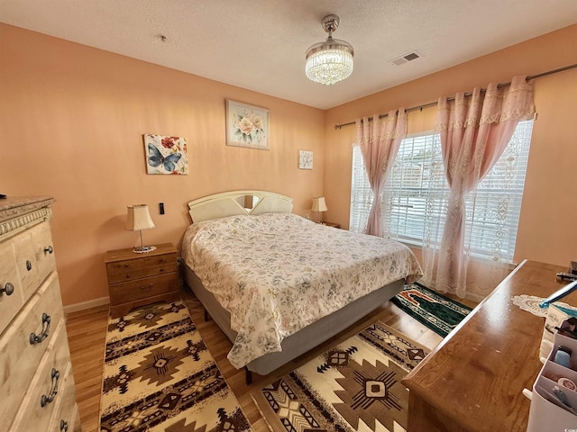 bedroom featuring a textured ceiling and light hardwood / wood-style flooring