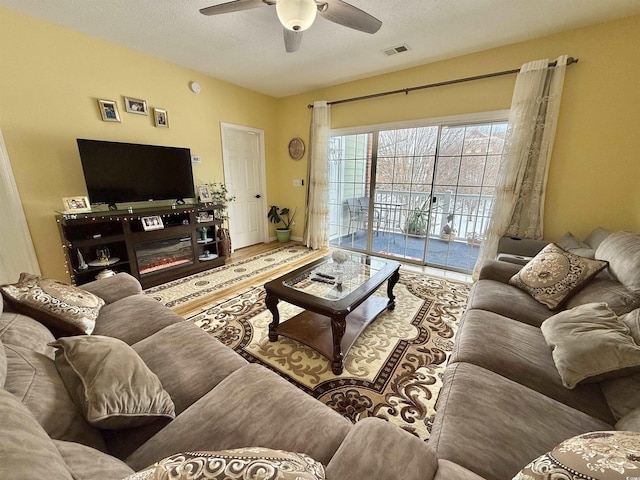 living room with ceiling fan, wood-type flooring, and a textured ceiling