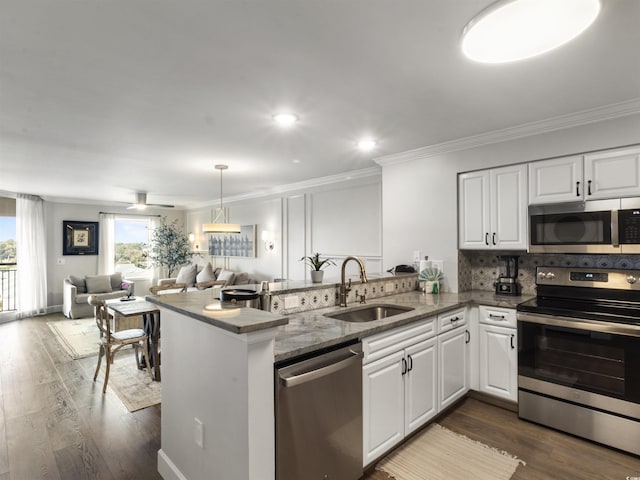 kitchen with a peninsula, a sink, white cabinets, appliances with stainless steel finishes, and open floor plan