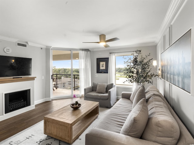 living area with visible vents, crown molding, a ceiling fan, and wood finished floors