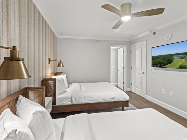 bedroom featuring visible vents, baseboards, wood finished floors, and ornamental molding