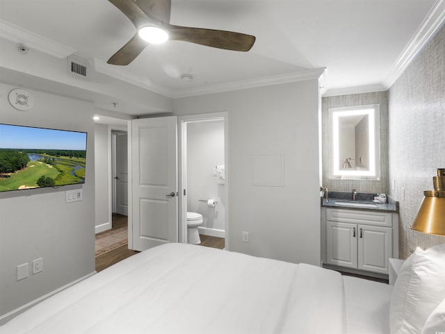 bedroom featuring visible vents, a sink, wood finished floors, connected bathroom, and crown molding