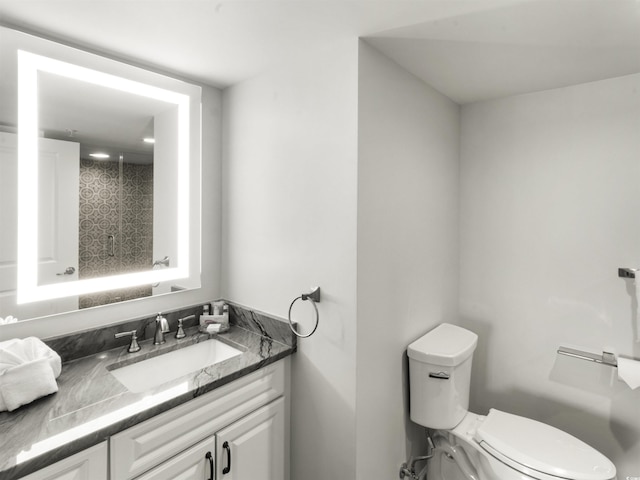 bathroom featuring toilet, vanity, and walk in shower