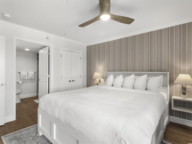 bedroom featuring ornamental molding, ensuite bathroom, wood finished floors, a closet, and baseboards