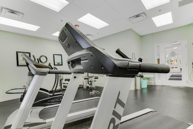 exercise room featuring visible vents, concrete block wall, and a drop ceiling