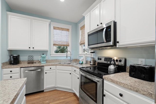 kitchen featuring white cabinetry, sink, stainless steel appliances, and light hardwood / wood-style floors