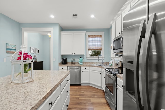 kitchen featuring stainless steel appliances, sink, white cabinets, and light hardwood / wood-style flooring