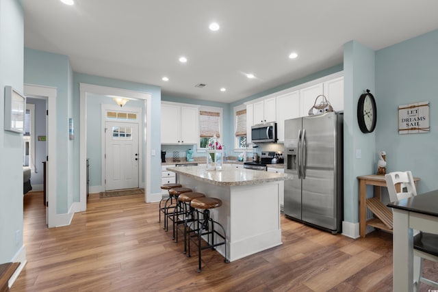 kitchen with white cabinetry, light hardwood / wood-style flooring, stainless steel appliances, and a center island