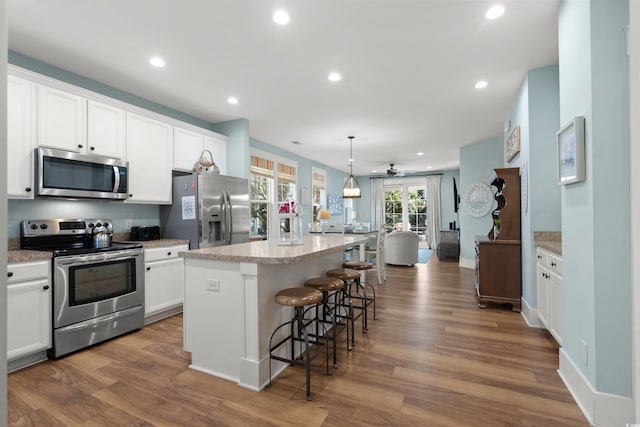 kitchen with stainless steel appliances, a center island, pendant lighting, and white cabinets