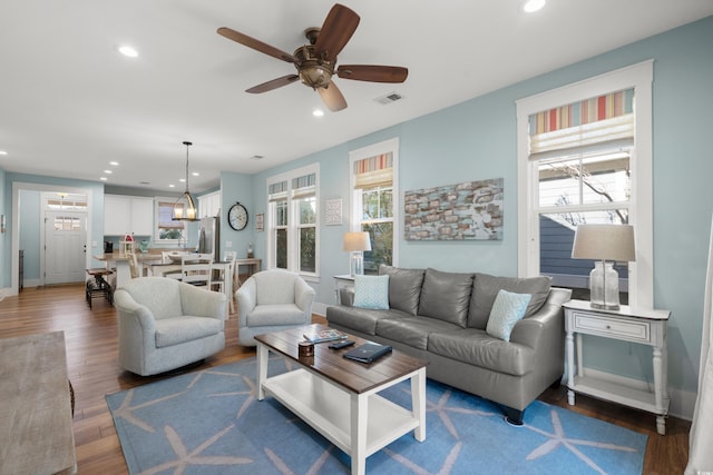 living room featuring dark wood-type flooring and ceiling fan