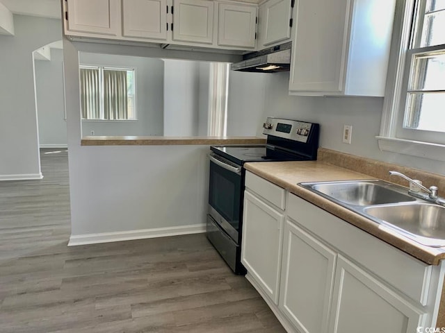 kitchen featuring stainless steel range with electric stovetop, sink, white cabinetry, and plenty of natural light