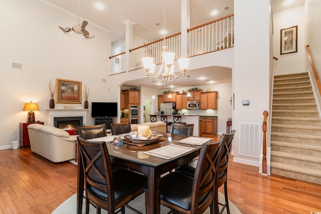 dining area with a towering ceiling, light hardwood / wood-style flooring, and a notable chandelier