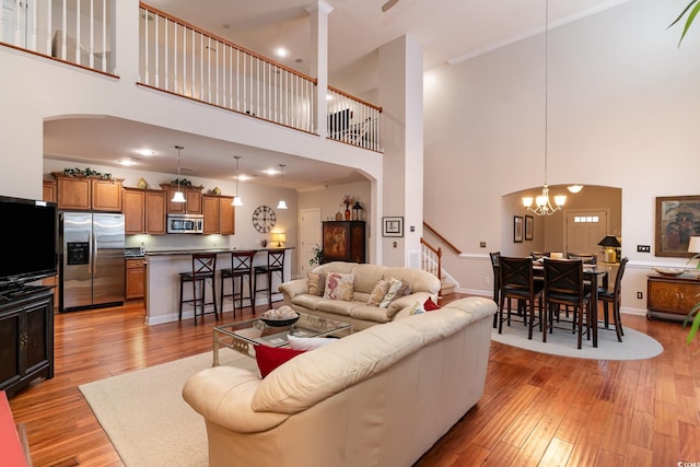 living room featuring a towering ceiling, a notable chandelier, and light hardwood / wood-style flooring