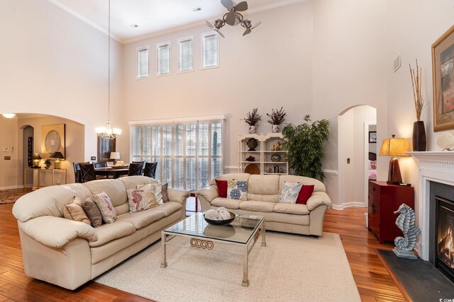 living room featuring crown molding, a notable chandelier, hardwood / wood-style flooring, and a towering ceiling