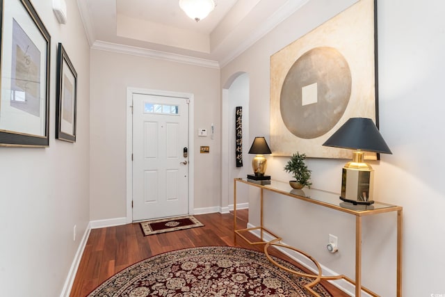 entryway with crown molding, wood-type flooring, and a tray ceiling