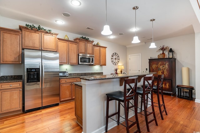 kitchen with pendant lighting, light hardwood / wood-style flooring, stainless steel appliances, and a kitchen island