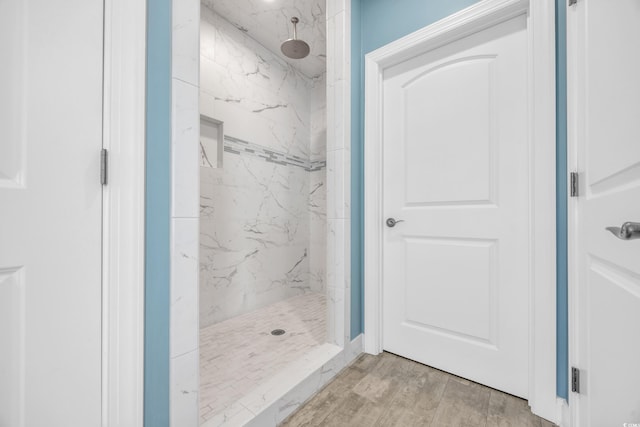 bathroom with hardwood / wood-style flooring and a tile shower