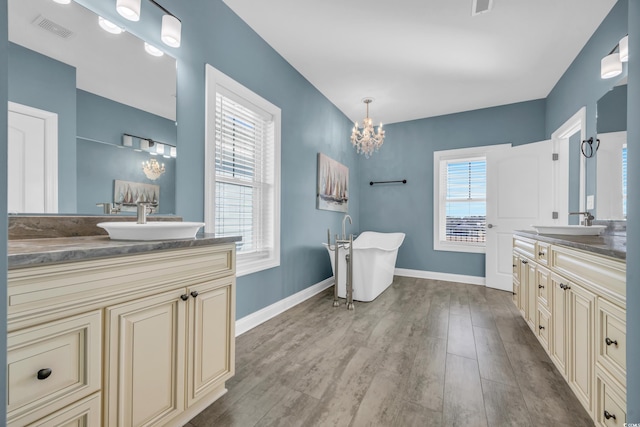 bathroom with a notable chandelier, wood-type flooring, a healthy amount of sunlight, and vanity