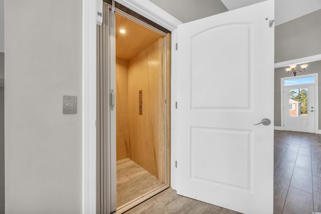 interior space with elevator, wood-type flooring, and a chandelier