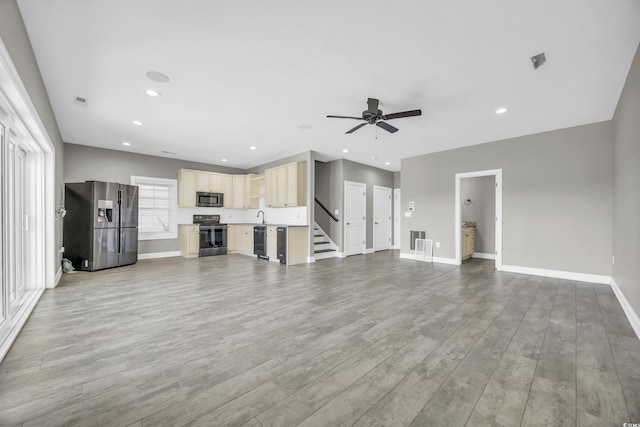 unfurnished living room featuring sink, ceiling fan, and light wood-type flooring