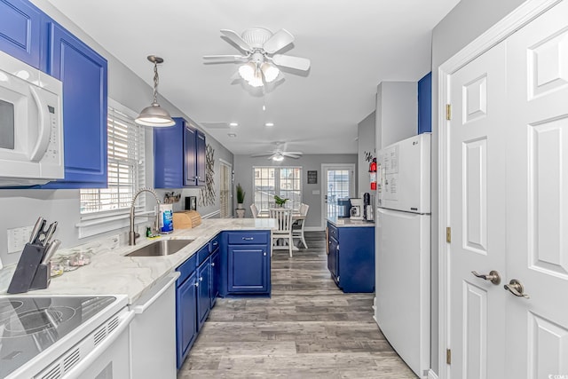 kitchen featuring blue cabinetry, sink, white appliances, and kitchen peninsula