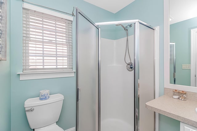 bathroom featuring a shower with door, vanity, and toilet