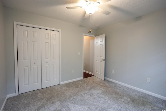 unfurnished bedroom featuring light colored carpet, a textured ceiling, ceiling fan, and a closet