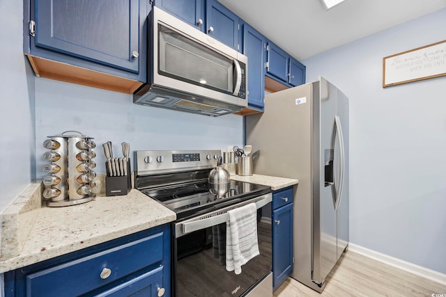 kitchen featuring light stone counters, light hardwood / wood-style flooring, stainless steel appliances, and blue cabinets