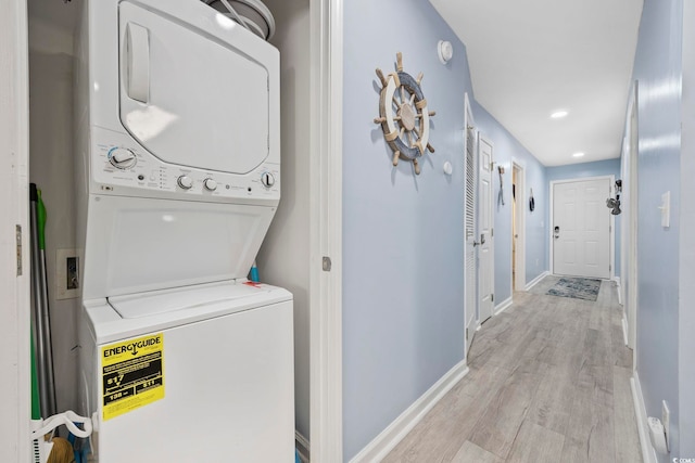 clothes washing area featuring stacked washer and dryer and light hardwood / wood-style flooring