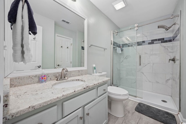 bathroom with wood-type flooring, toilet, a shower with shower door, and vanity