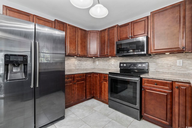 kitchen featuring tasteful backsplash, decorative light fixtures, light tile patterned floors, appliances with stainless steel finishes, and light stone countertops