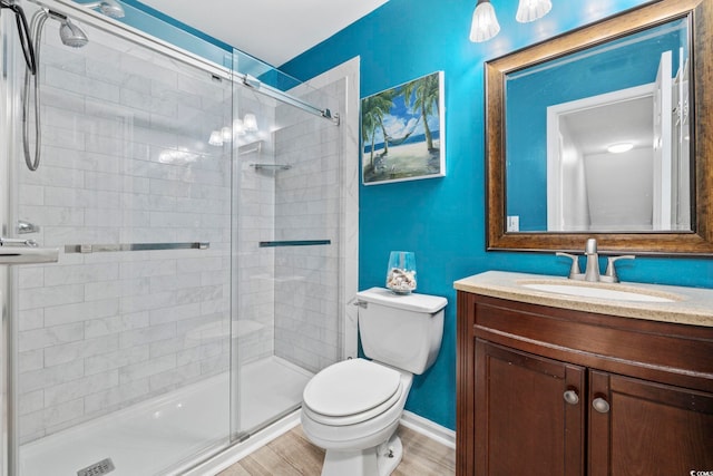 bathroom with hardwood / wood-style flooring, walk in shower, vanity, and toilet