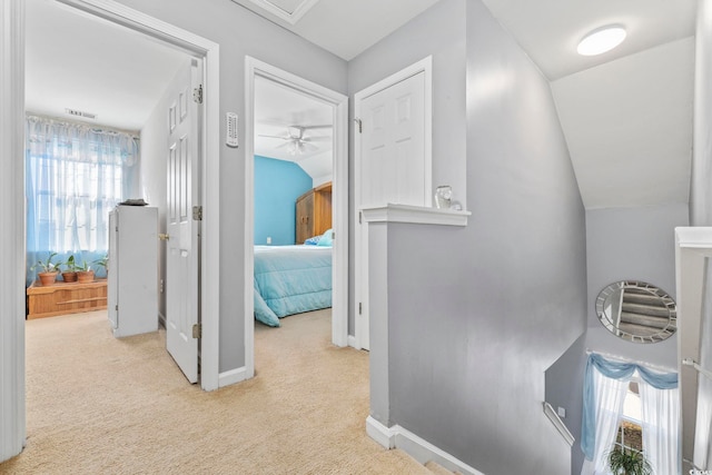 hallway featuring light colored carpet, a healthy amount of sunlight, and vaulted ceiling