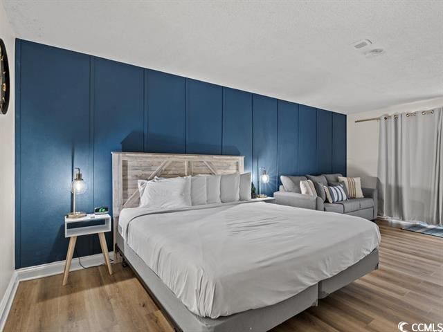 1205 S Ocean Blvd Unit 50412, Myrtle Beach, SC 29577 - bedroom featuring a decorative wall and wood finished floors