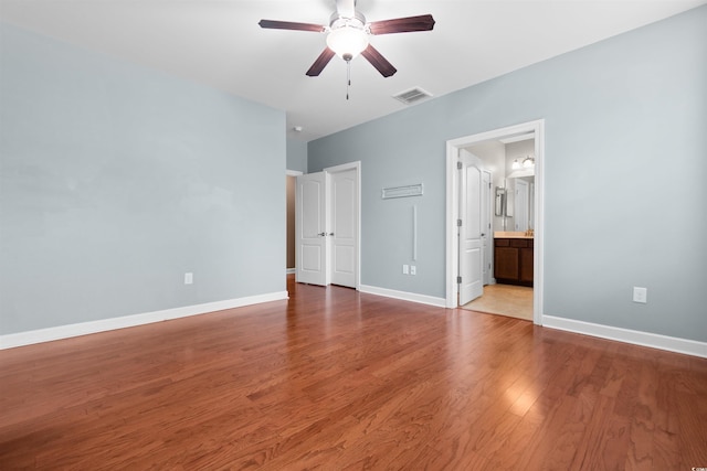 unfurnished bedroom with ceiling fan, ensuite bath, and wood-type flooring