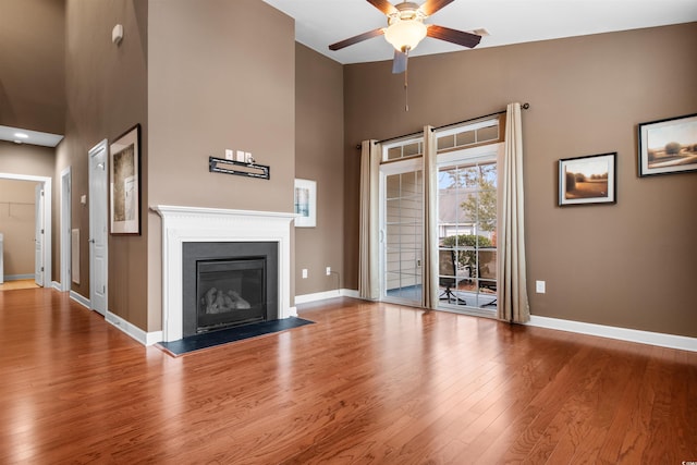 unfurnished living room featuring ceiling fan, hardwood / wood-style floors, and a high ceiling