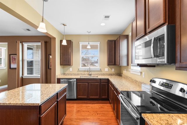 kitchen featuring pendant lighting, sink, dark hardwood / wood-style flooring, light stone counters, and stainless steel appliances