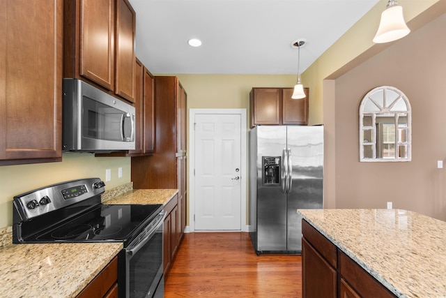 kitchen with light stone counters, hanging light fixtures, dark hardwood / wood-style flooring, and stainless steel appliances