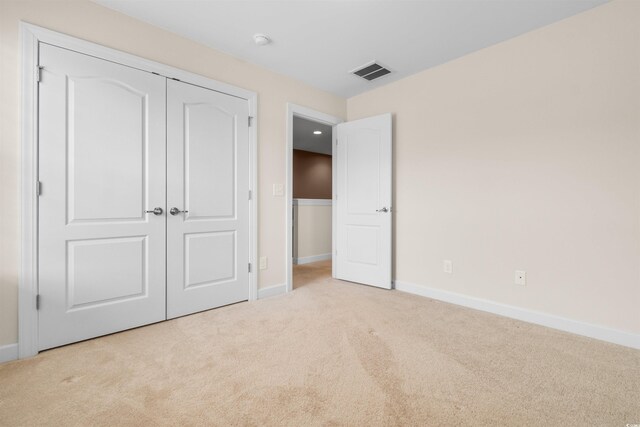 unfurnished bedroom featuring light colored carpet and a closet