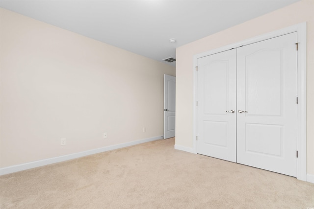 unfurnished bedroom featuring light carpet and a closet