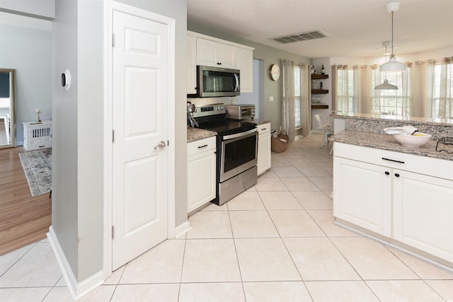 kitchen with appliances with stainless steel finishes, white cabinets, stone countertops, decorative light fixtures, and light tile patterned flooring