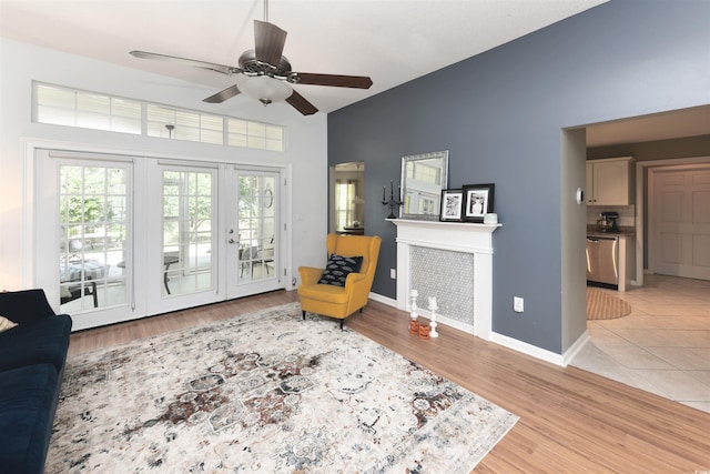 living area with lofted ceiling, light tile patterned floors, a tile fireplace, and ceiling fan