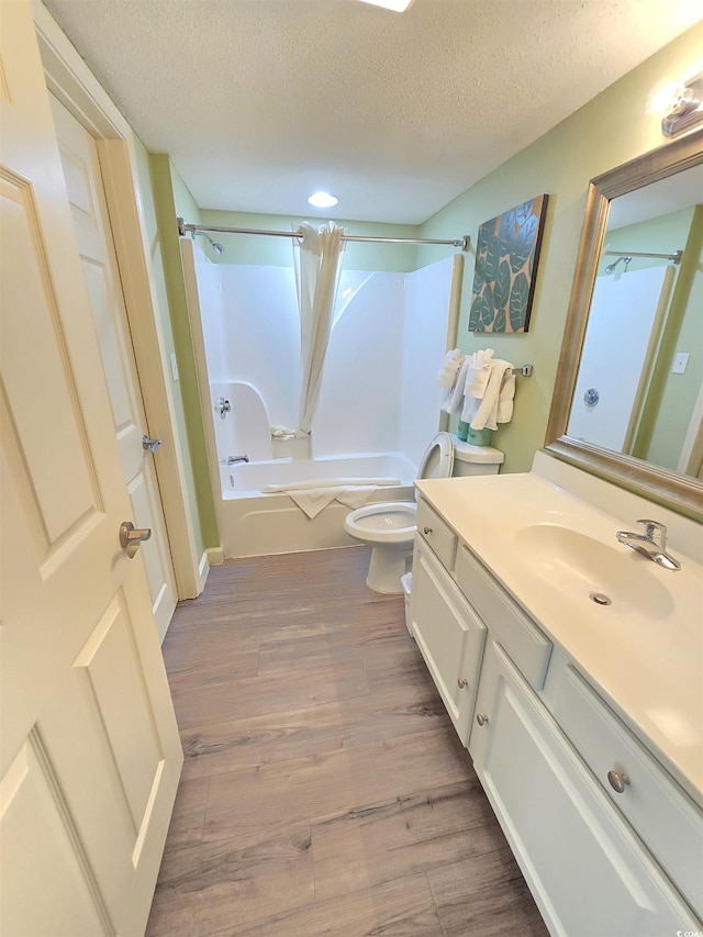 full bathroom featuring shower / bathing tub combination, hardwood / wood-style flooring, vanity, toilet, and a textured ceiling