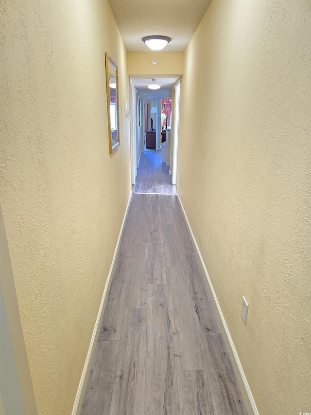 hallway with hardwood / wood-style flooring and a textured ceiling