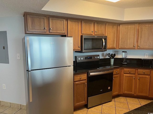 kitchen featuring a textured ceiling, appliances with stainless steel finishes, electric panel, and brown cabinets