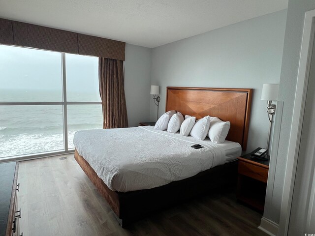 bedroom with a water view and wood finished floors