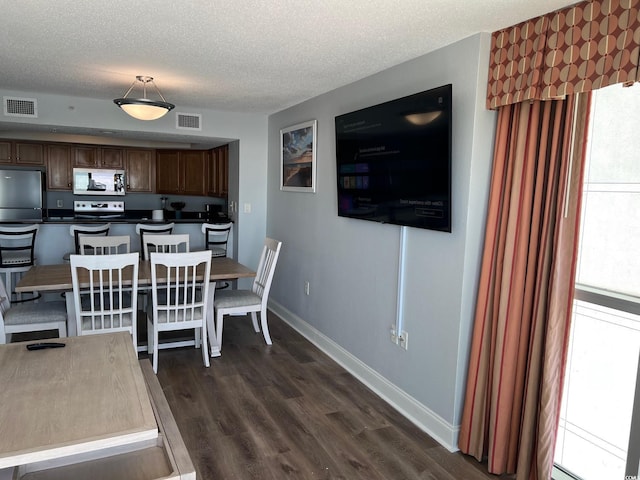 dining space featuring dark wood-style floors, visible vents, a textured ceiling, and baseboards