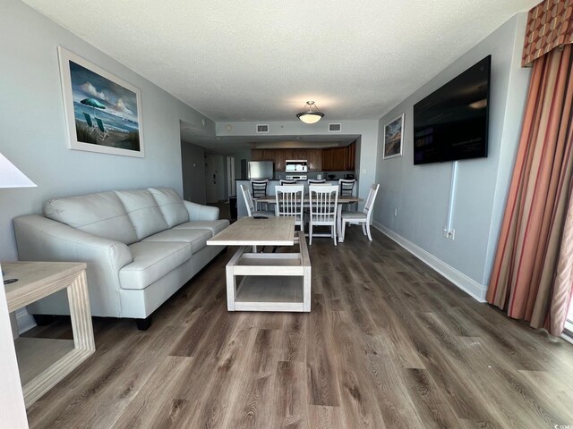 living room with visible vents, dark wood finished floors, a textured ceiling, and baseboards