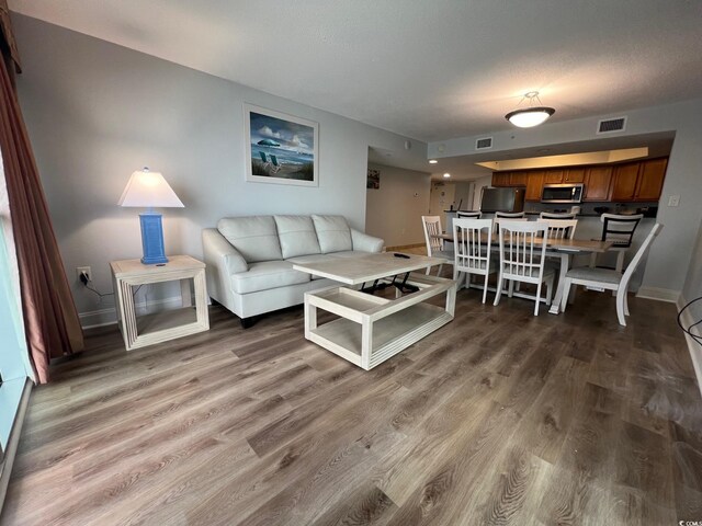 living room with baseboards, visible vents, and wood finished floors